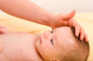 Mamma accarezza la fontanella neonato, cura del bambino