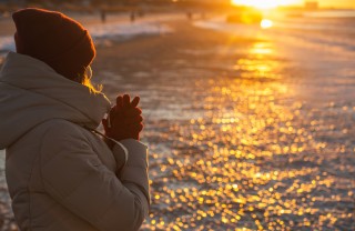 Una donna guarda il sole d'inverno solstizio inverno cosa fare, solstizio inverno