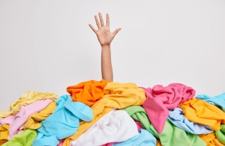 una mano che spunta da una massa di vestiti quando fare decluttering, fare decluttering